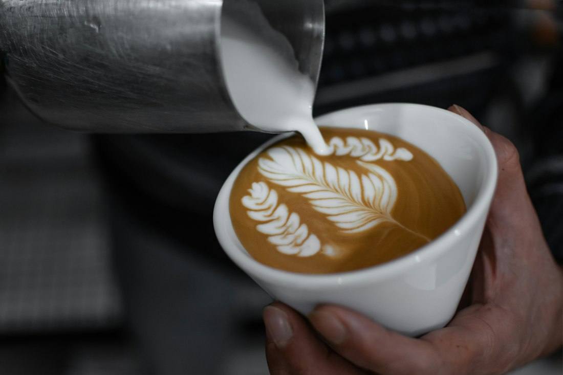 Barista pouring latte art into a cup
